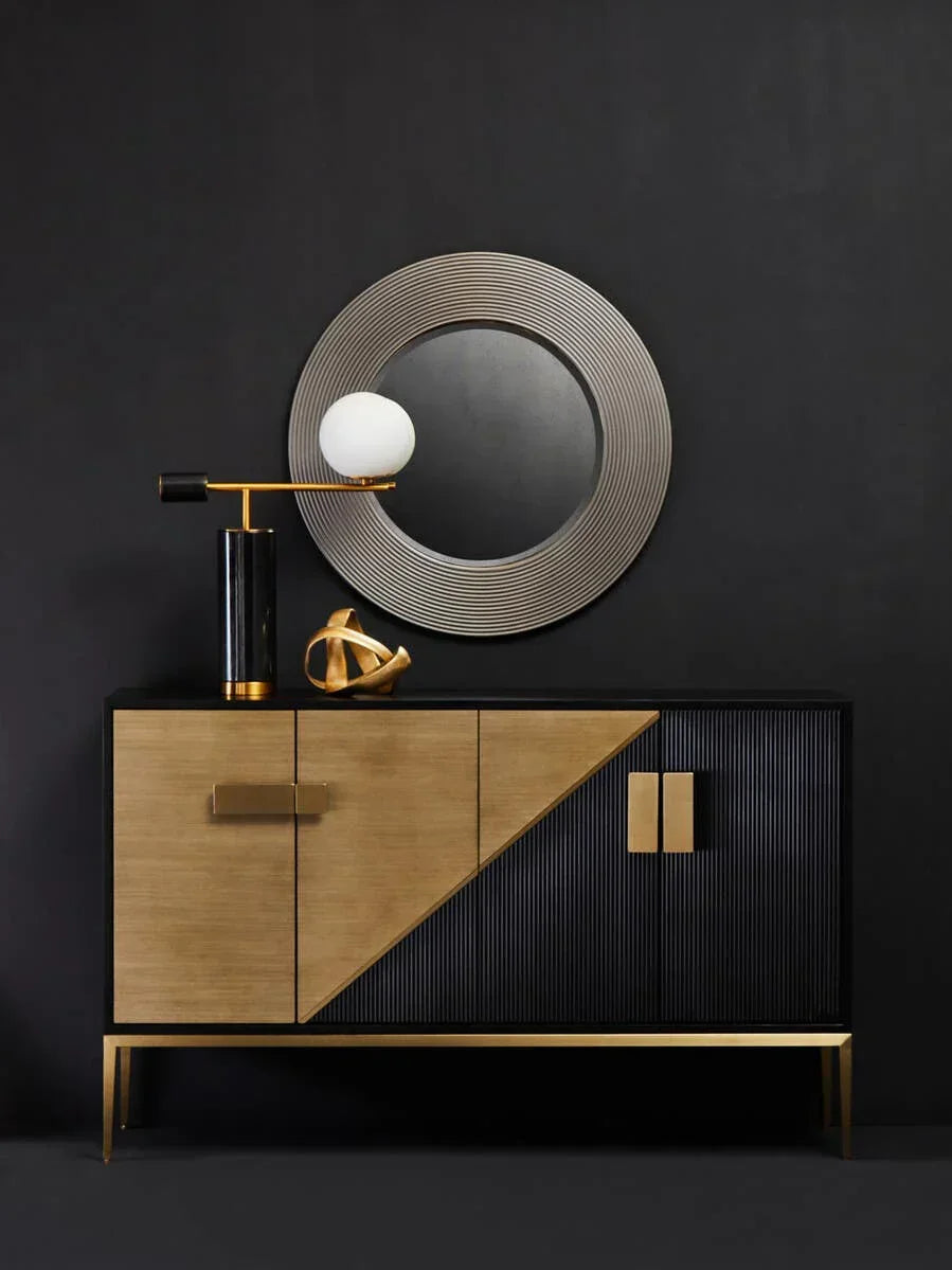 Modern sideboard with gold and black doors, round mirror, and decorative lamp on top