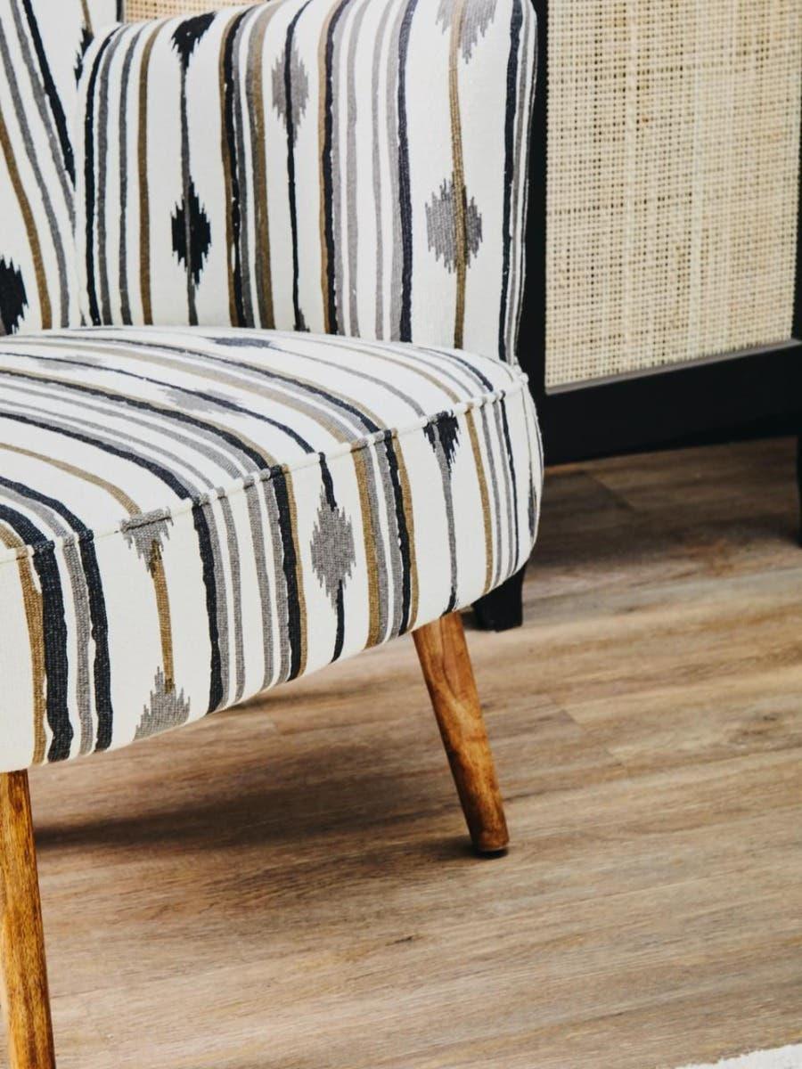 Striped upholstered accent chair with wooden legs on laminate floor