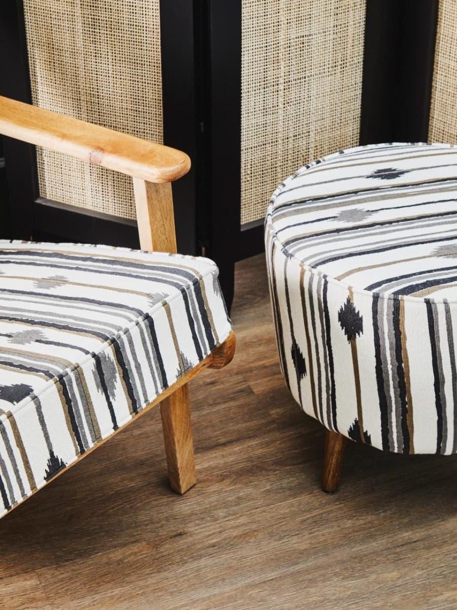 Wooden armchair and round ottoman with black and beige striped upholstery on wood floor
