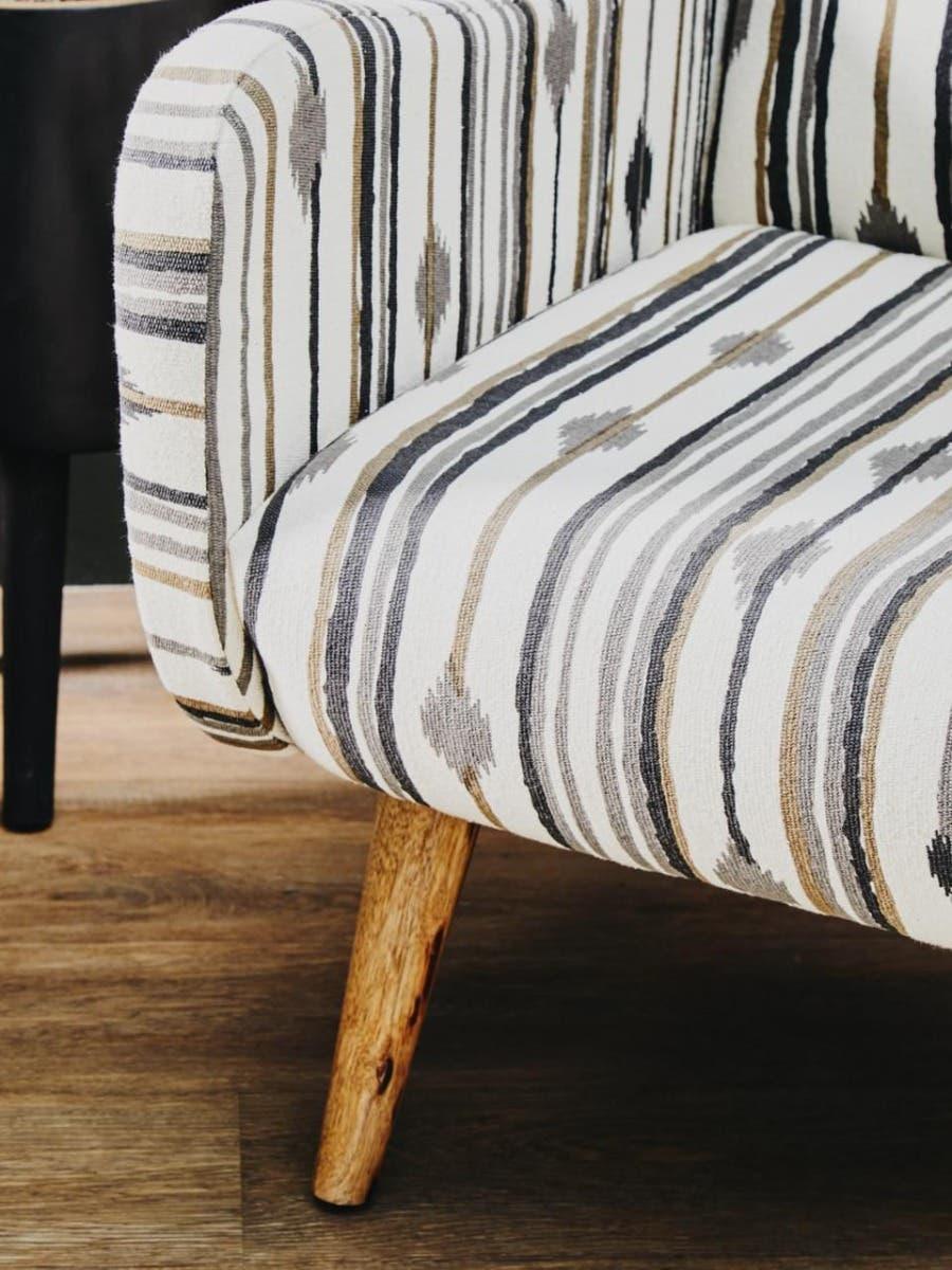 Striped fabric sofa with wooden legs on wood flooring, close-up of armrest and seat