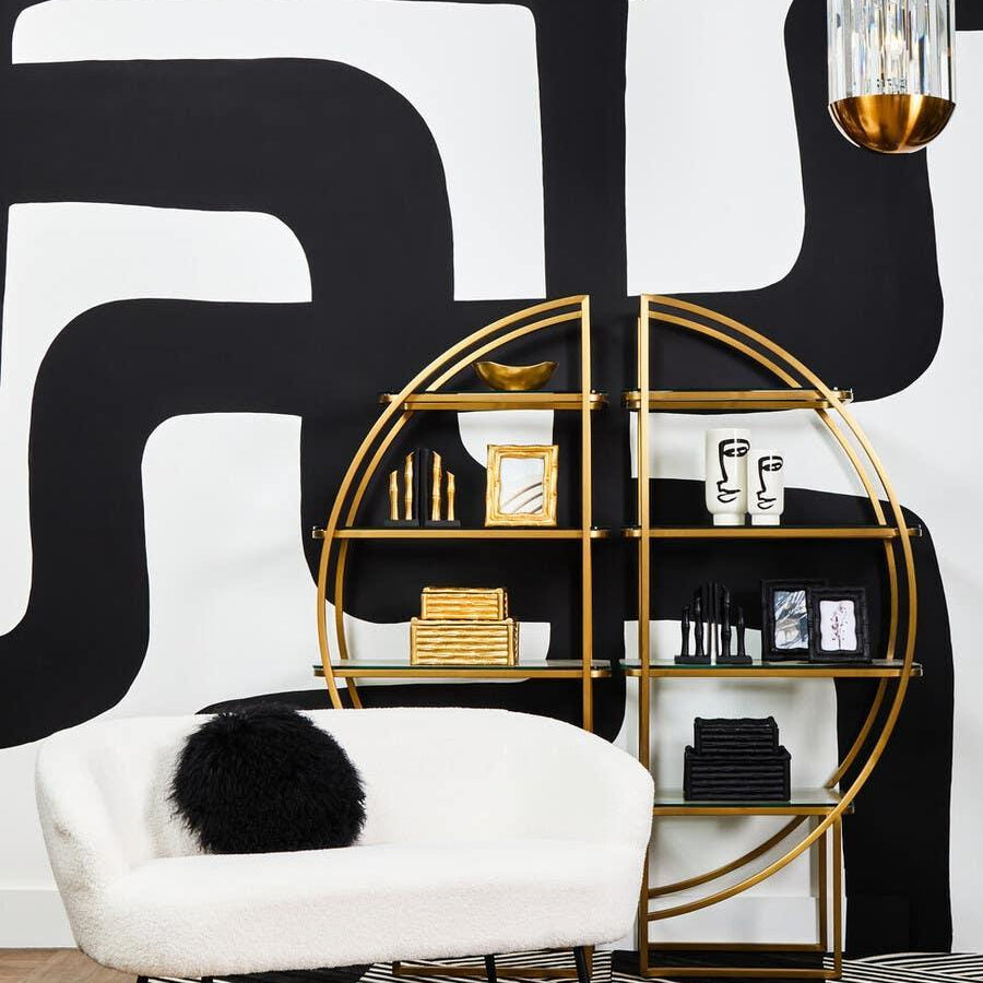 White boucle loveseat with black pillow on geometric rug, gold round shelving, modern decor