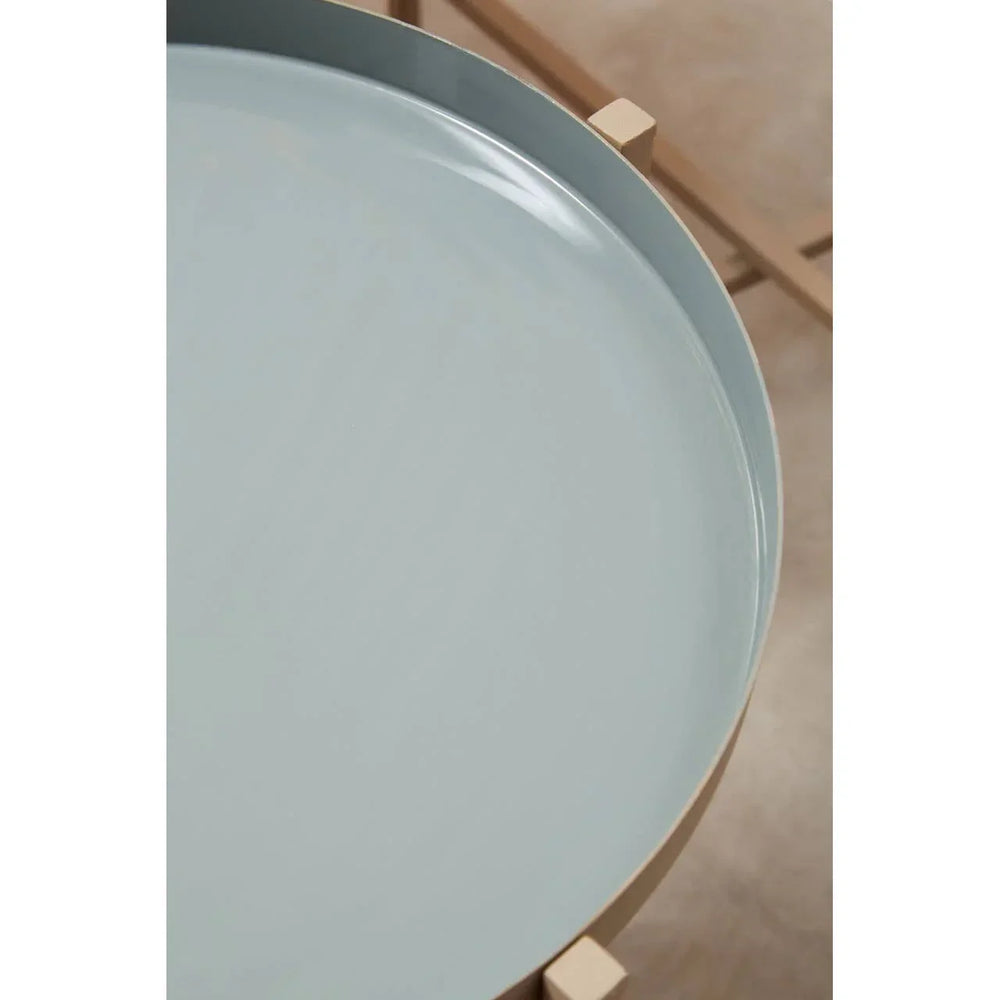 Closeup of round light blue metal tray table top with wooden legs