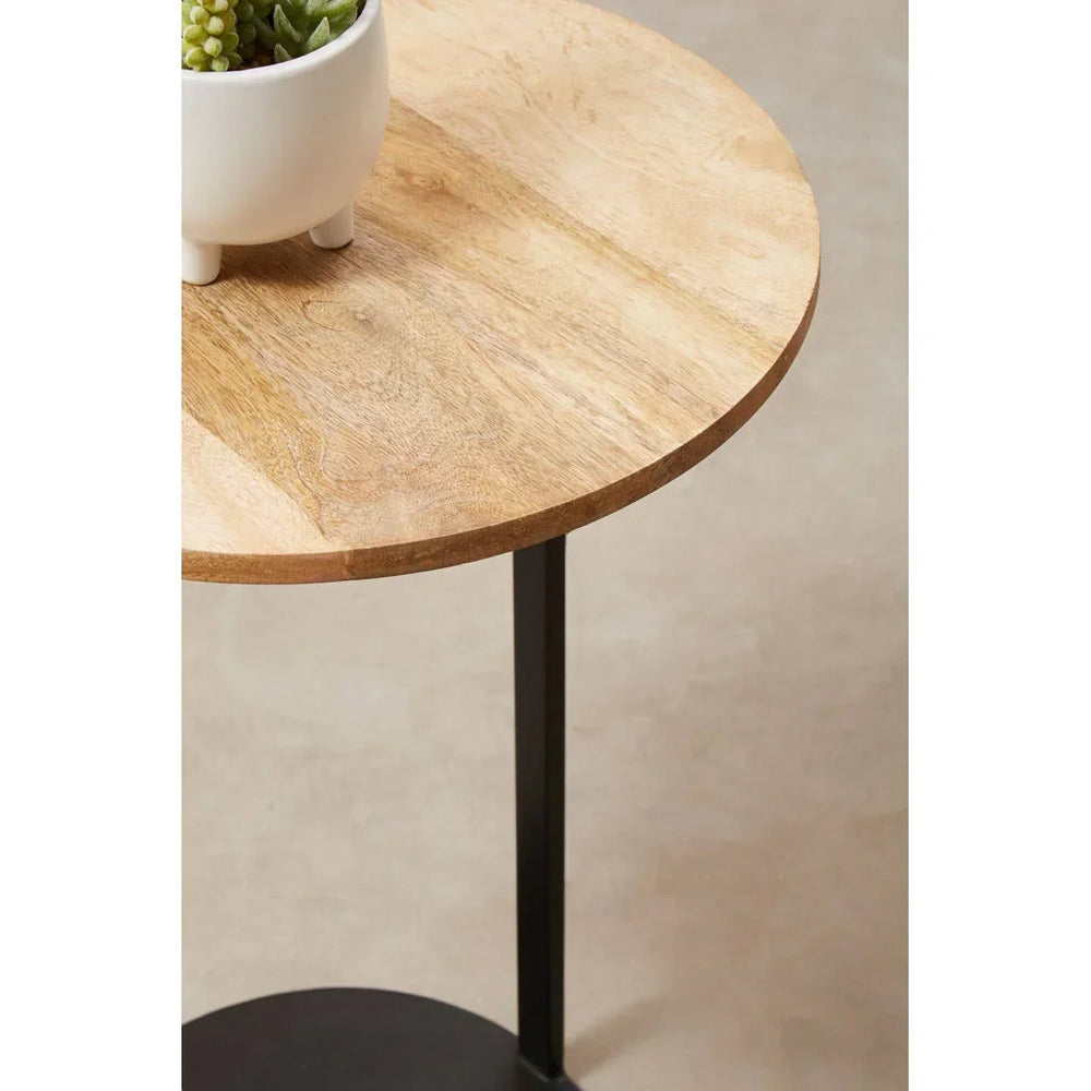Round wooden side table with black metal legs and a small plant pot on top