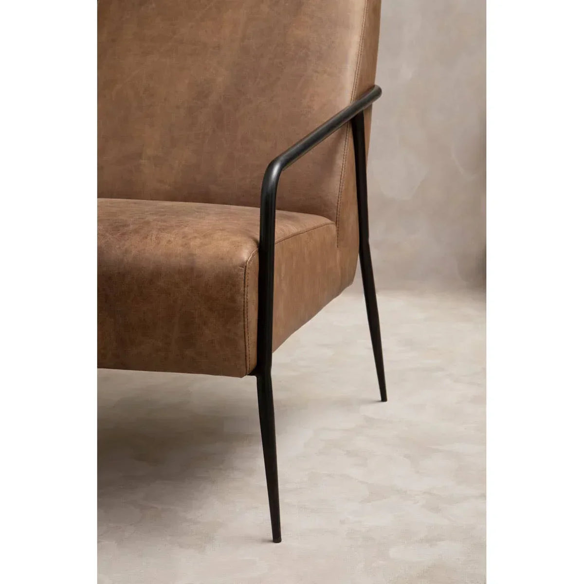 Brown leather armchair with black metal legs and armrest, side view on neutral background