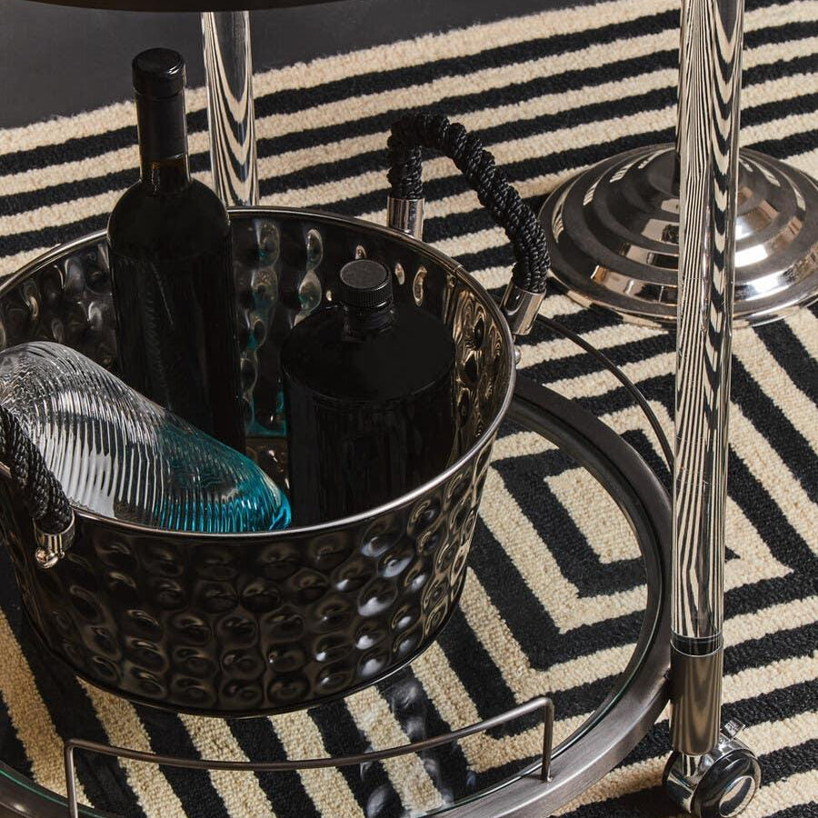 Modern metal drinks trolley with glass shelves on black and cream geometric rug