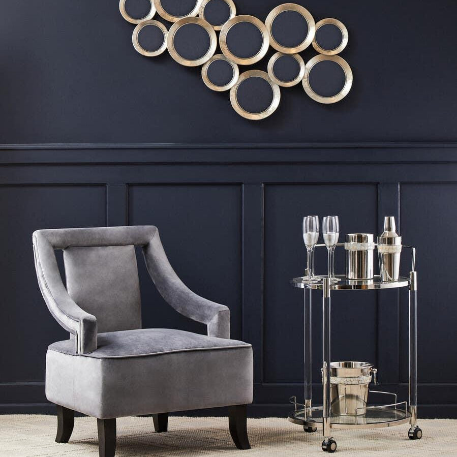 Grey velvet accent chair beside chrome drinks trolley on cream textured rug