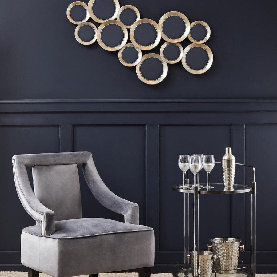 Grey accent chair with black legs beside round metal drinks trolley on beige rug