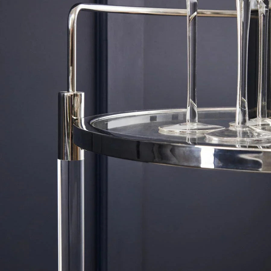 Chrome and glass drinks trolley corner with four champagne flutes, modern home bar cart