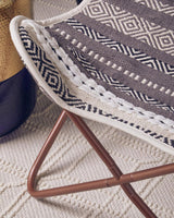 Grey and white butterfly chair featuring a woven seat with a geometric pattern and a sturdy metal frame in a warm brown finish, placed on a textured light-colored rug