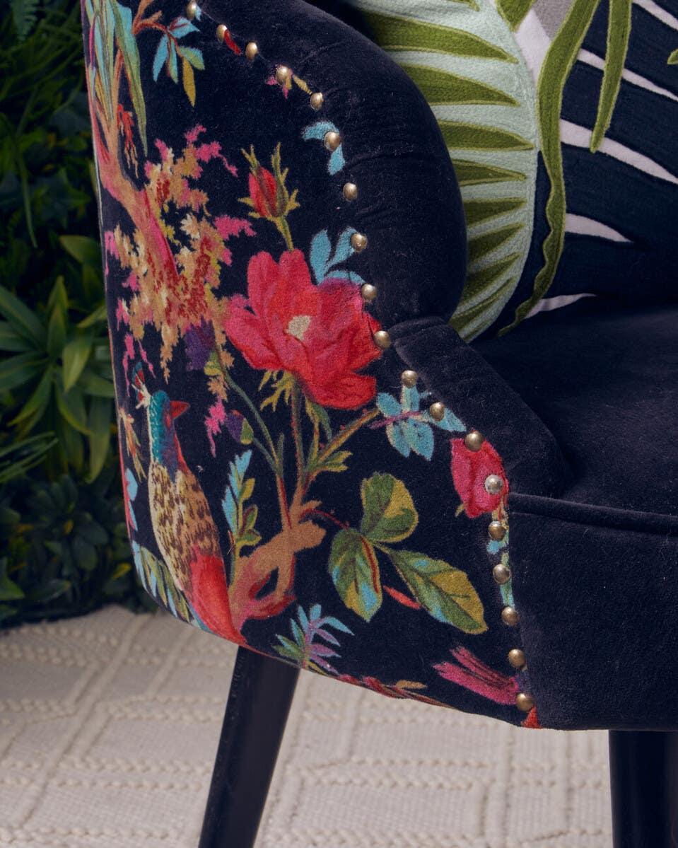 Velvet accent chair with floral upholstery, gold studs and black wooden legs