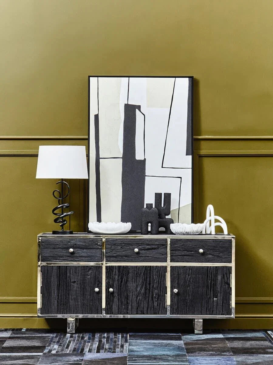 Black wood sideboard with chrome trim, abstract art, lamp, and ceramic decor on display