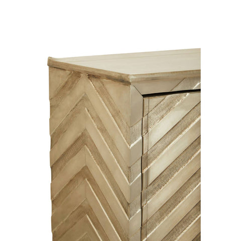 A close-up view of the Sirsa Two Door Cabinet featuring a light wood finish with a chevron pattern on the front. The cabinet has two doors with a sleek handle and a smooth top surface. The overall design is modern and stylish, suitable for home decor