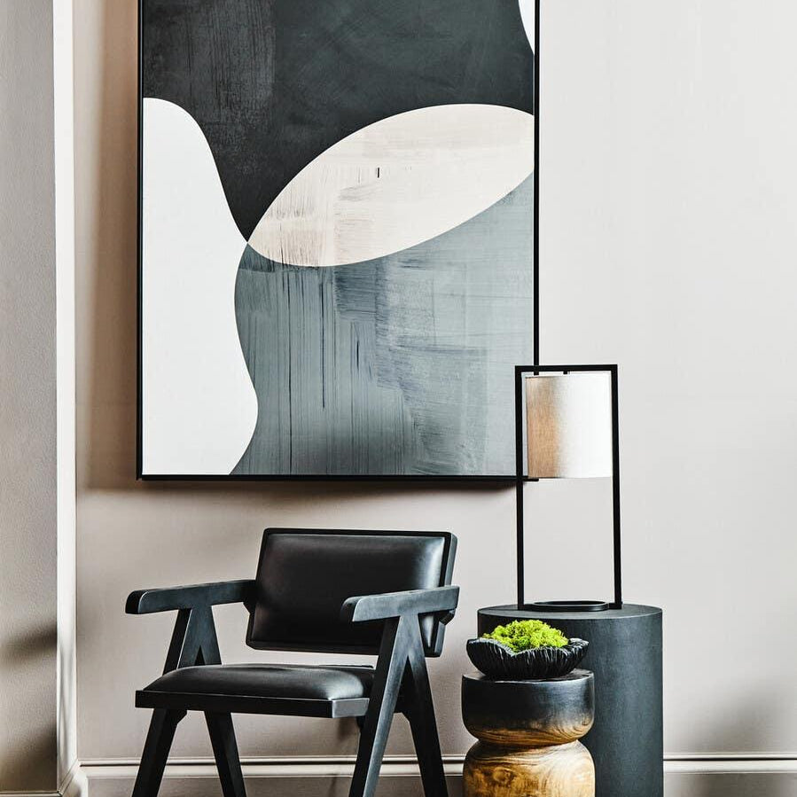 Modern black accent chair with side tables, lamp and abstract wall art in living room