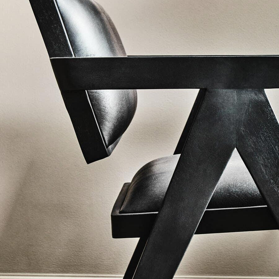 Side view of modern black leather dining chair with angled wooden frame