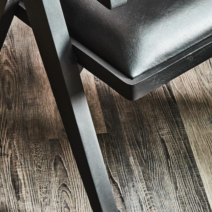 Modern black dining chair with faux leather seat and angled wooden legs on wood floor