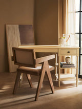 Wooden accent chair with beige upholstery beside cream writing desk in sunlit room