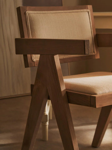 Modern wooden dining chair with beige cushioned seat and backrest, angled side view