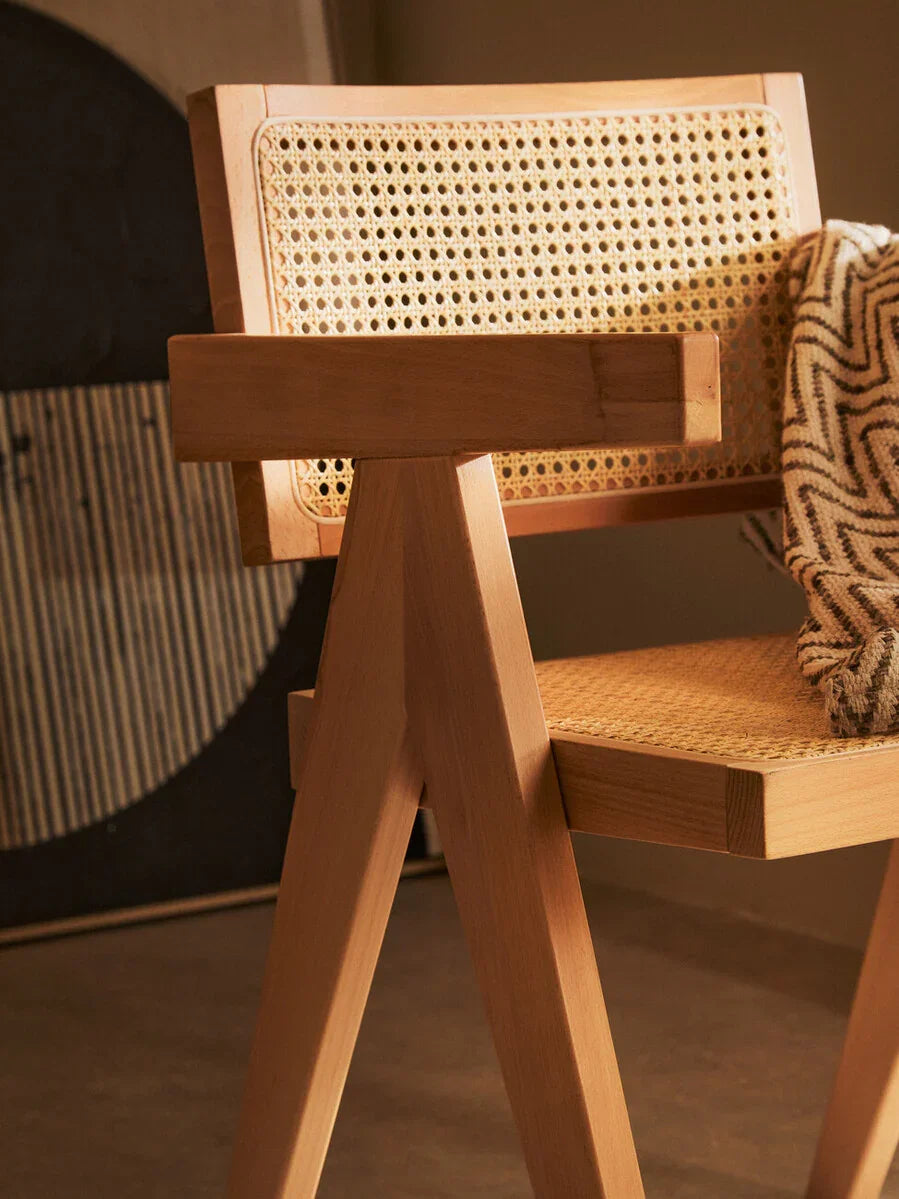 Wooden dining chair with woven cane seat and backrest, geometric frame, zigzag throw draped