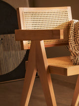 Wooden dining chair with woven cane seat and backrest, geometric frame, zigzag throw draped