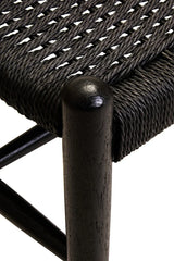 Close up of black woven chair seat with solid wood leg and textured rope details