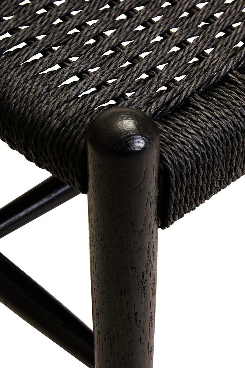 Close up of black woven chair seat with solid wood leg and textured rope details