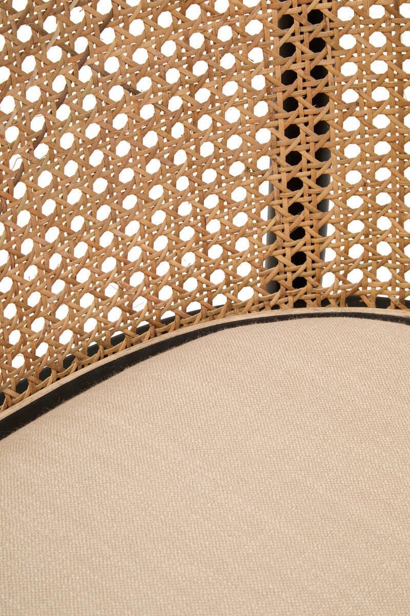 Close-up of rattan chair backrest with woven cane and beige fabric seat