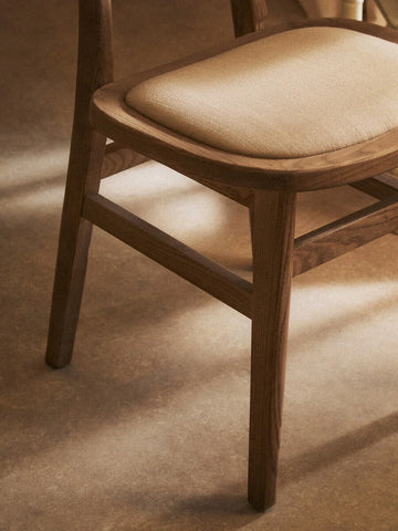 Oak dining chair with light beige fabric seat cushion, side view on wood floor