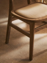 Oak dining chair with light beige fabric seat cushion, side view on wood floor