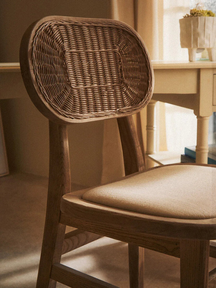 Wooden dining chair with woven rattan backrest and fabric seat near cream table