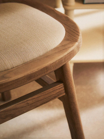 Close-up of wooden dining chair with beige upholstered seat