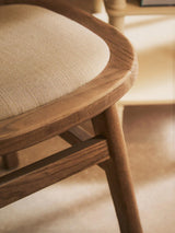 Close-up of wooden dining chair with beige upholstered seat