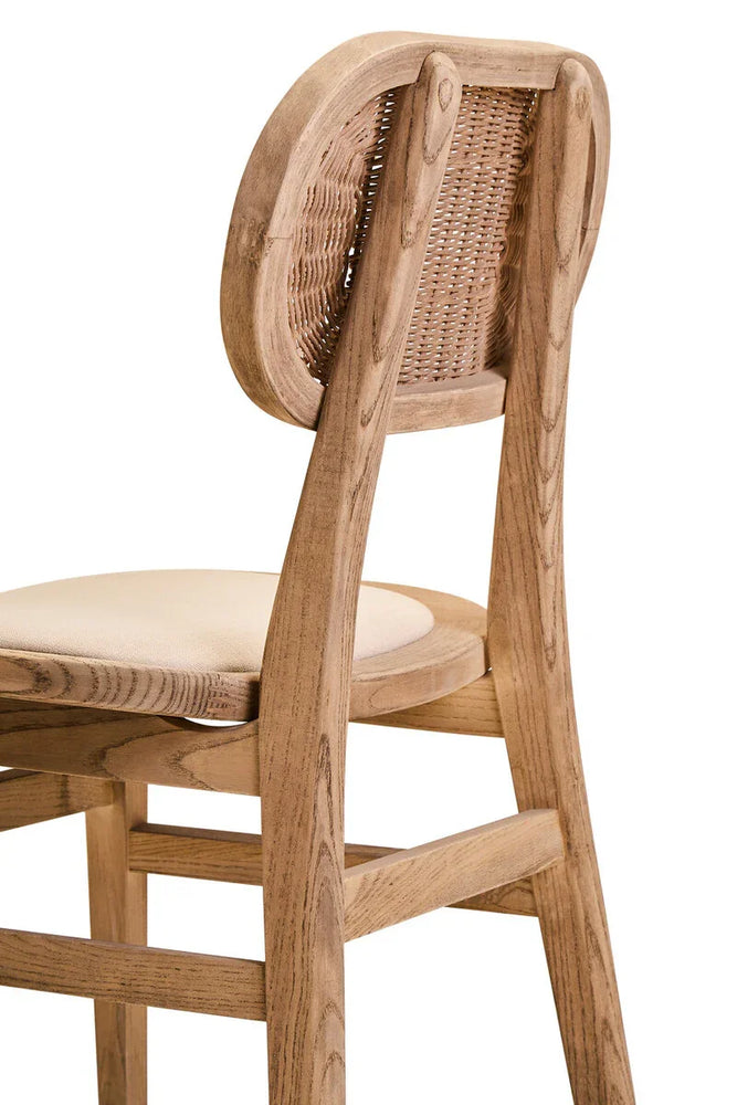 Light oak dining chair with cream cushioned seat and curved rattan backrest, side view