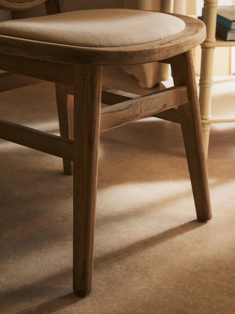 Oak dining chair with light fabric seat cushion, angled side view on wooden floor