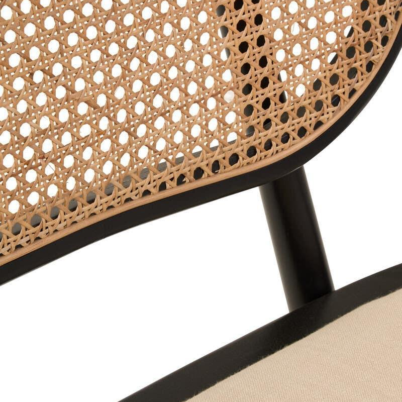 Close up of rattan dining chair with black frame and beige cushioned seat
