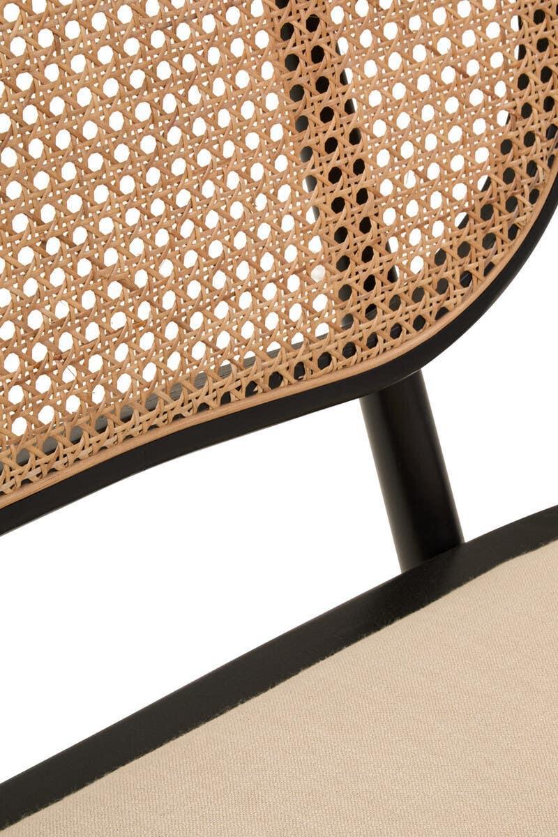 Close up of rattan dining chair with black frame and beige cushioned seat