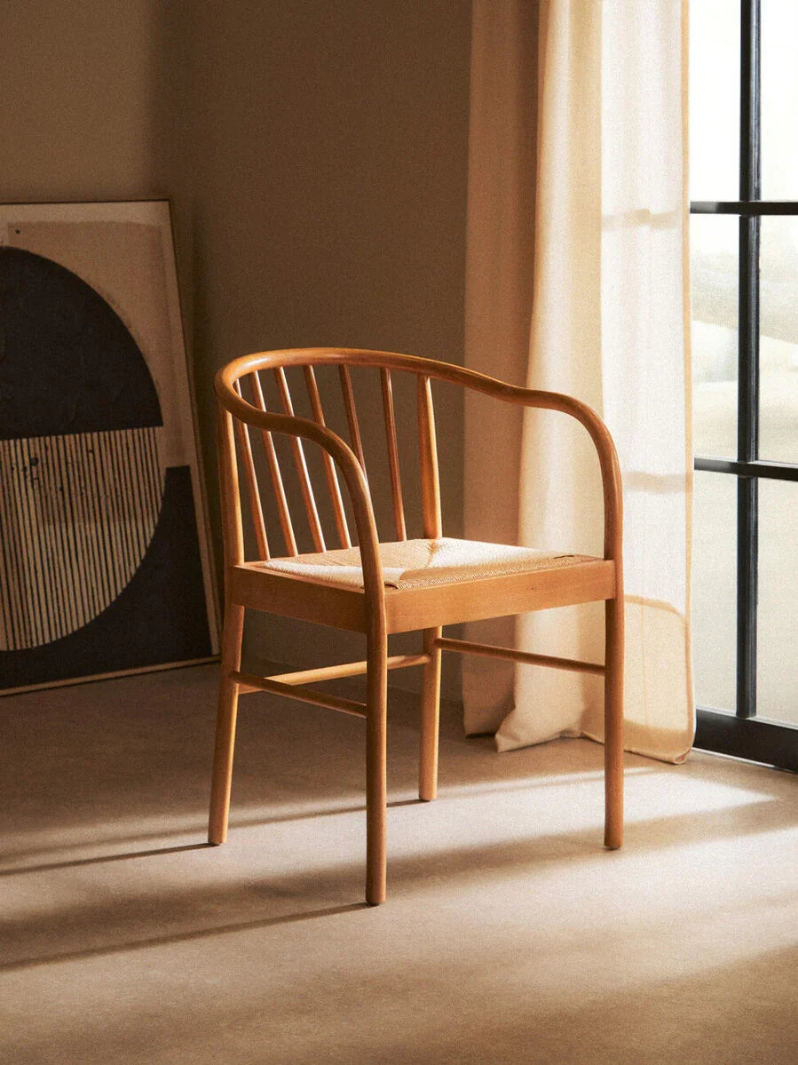 Natural wood dining chair with curved backrest and woven seat by sunlit window