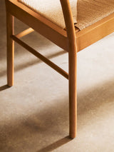 Closeup of wooden dining chair with woven seat on light floor