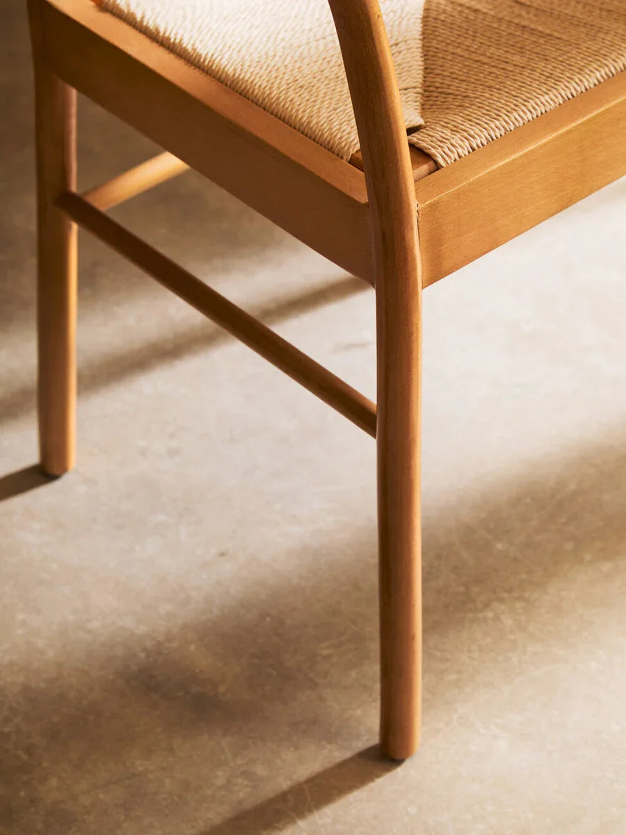 Closeup of wooden dining chair with woven seat on light floor