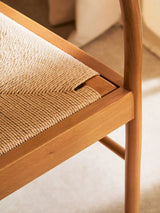 Close view of wooden dining chair with woven natural cord seat and curved leg detail