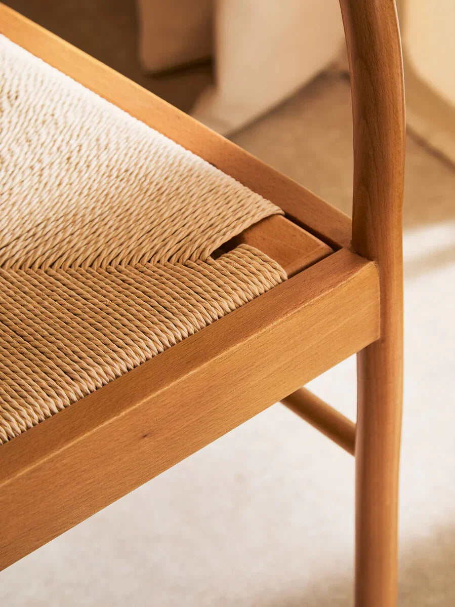 Close view of wooden dining chair with woven natural cord seat and curved leg detail