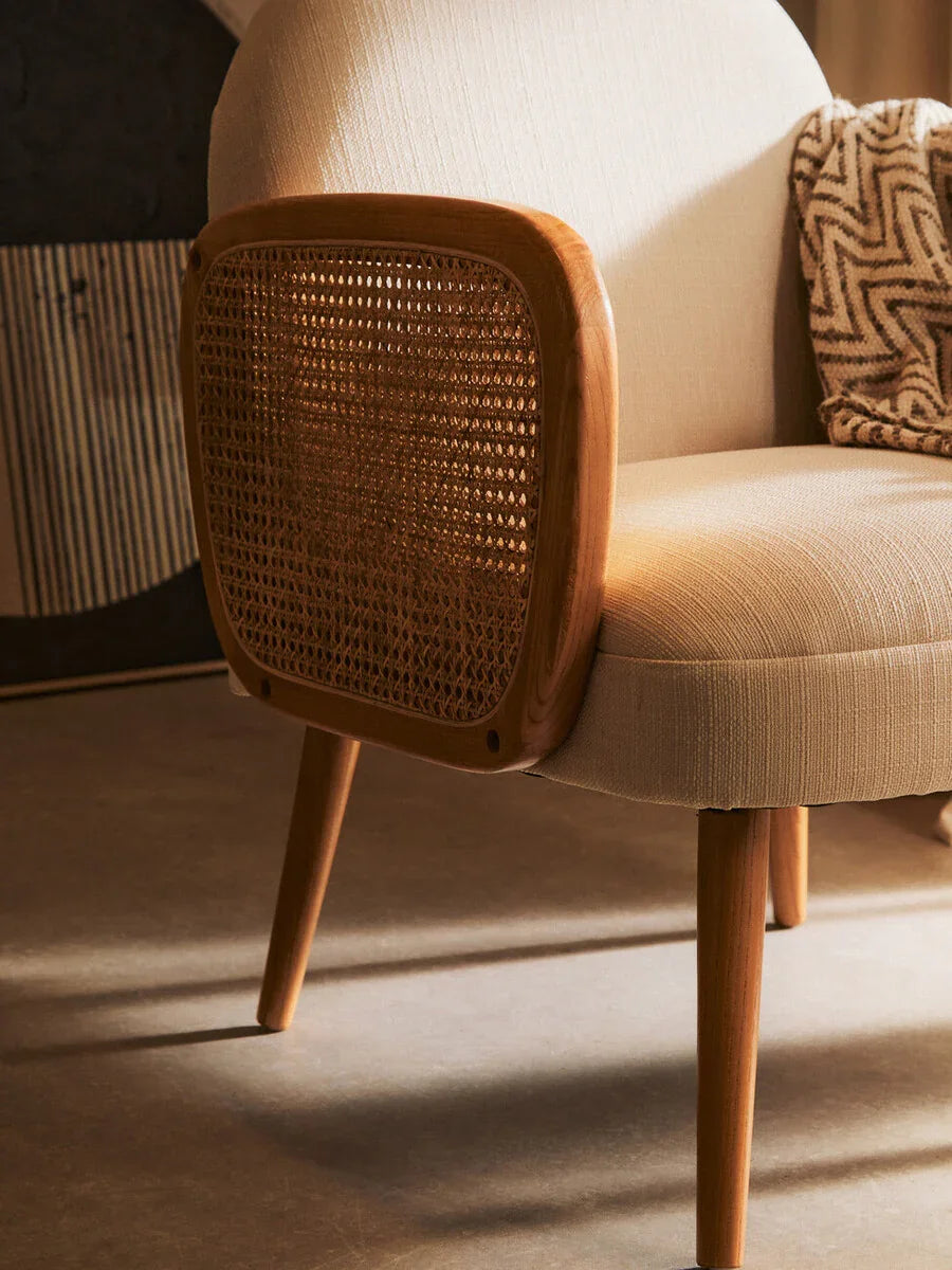 Beige accent chair with rattan wood arm detail and chevron throw blanket on the armrest