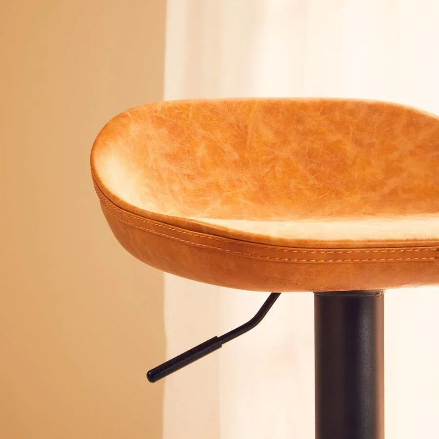 Tan leather bar stool seat with black metal base and adjustable lever, side view