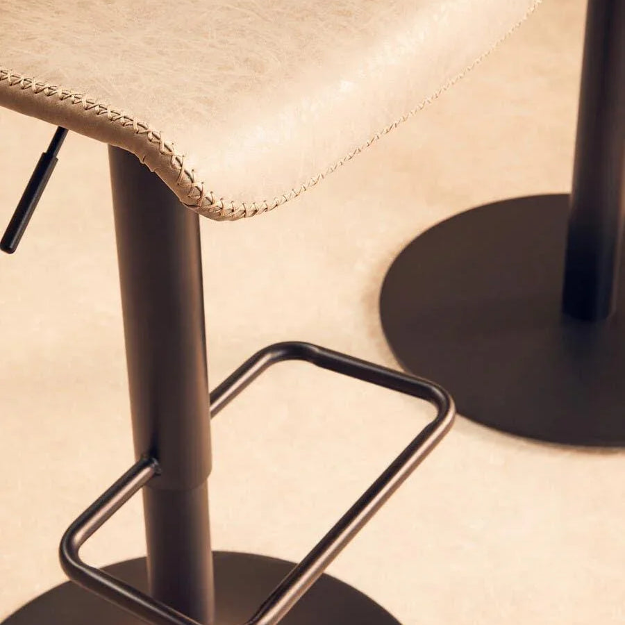 Close-up of beige faux leather bar stool with black metal base and footrest