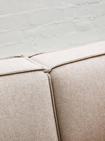 Close-up view of the Toulouse Natural Fabric Armless Modular Sofa, highlighting the soft beige fabric and the seam detail where two sections meet, set against a light-colored floor
