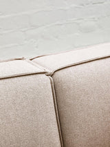Close-up view of the Toulouse Natural Fabric Armless Modular Sofa, highlighting the soft beige fabric and the seam detail where two sections meet, set against a light-colored floor