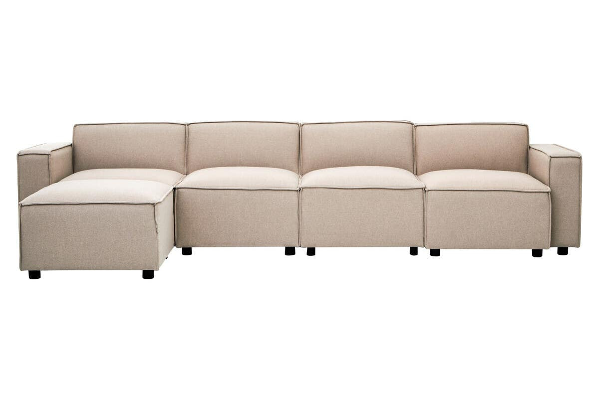 Modular ottoman in natural fabric featuring a contemporary design with clean lines, arranged in a sectional layout. The ottoman has a light beige color and is supported by small, dark legs, providing a modern aesthetic suitable for various living spaces