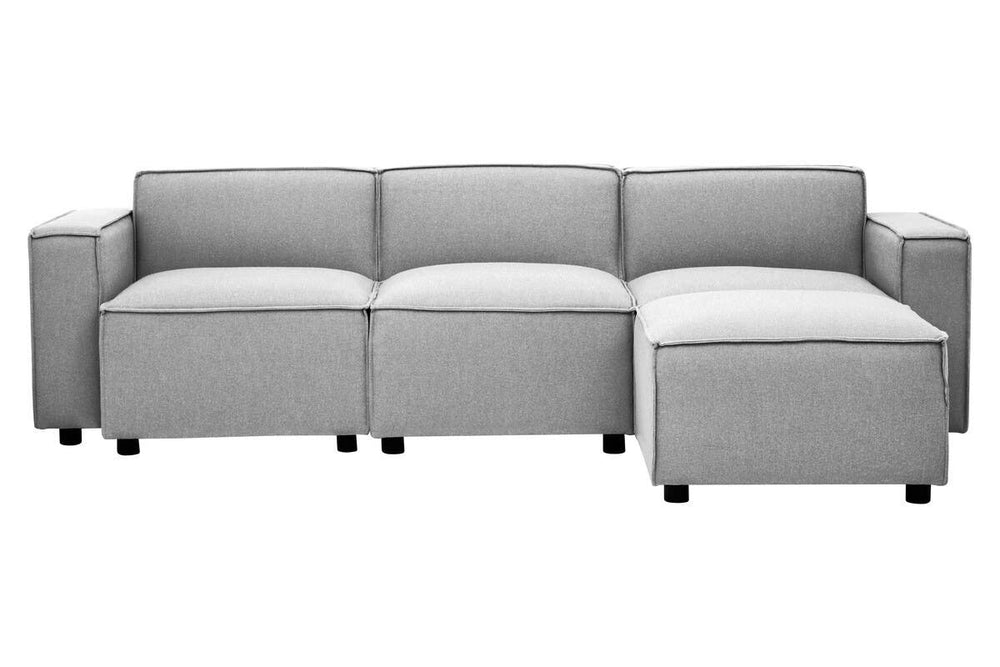 Grey fabric armless modular sofa featuring a sleek design with three cushioned sections and a chaise lounge on one end, supported by small black legs. The upholstery has a smooth texture, and the overall look is modern and minimalist