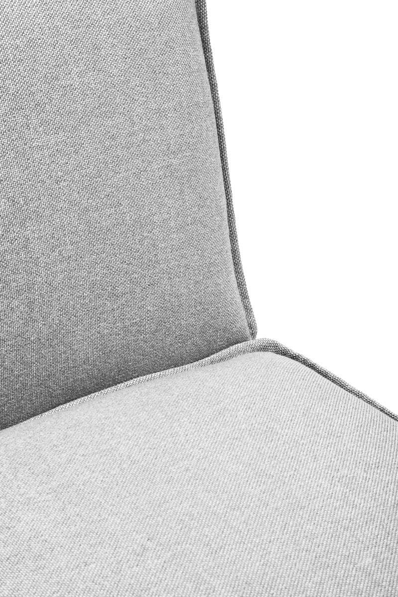 Soft grey fabric upholstery covers the armless section of a modular sofa, featuring a clean, modern design with a slightly angled backrest and subtle piping along the edges. The texture appears smooth and inviting, suitable for contemporary home decor