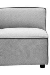 Left arm section of a modular sofa upholstered in light grey fabric, featuring a smooth, cushioned seat and a slightly curved backrest. The base is solid and includes small black feet for stability