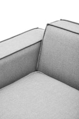 Close-up view of the corner of a grey fabric modular sofa featuring a left armrest, showcasing the smooth texture and clean lines of the upholstery. The cushion has a subtle seam detail along the edges